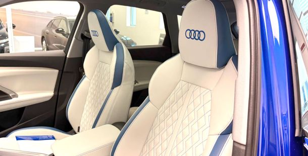 sedili anteriori auto bianchi con bordi e cuciture blu e logo Audi blu ricamato sul poggiatesta