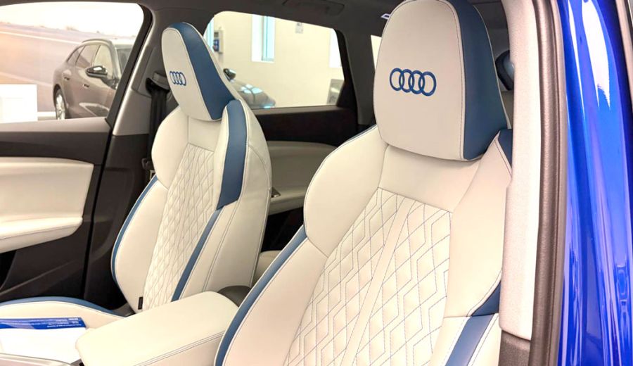 sedili anteriori auto bianchi con bordi e cuciture blu e logo Audi blu ricamato sul poggiatesta
