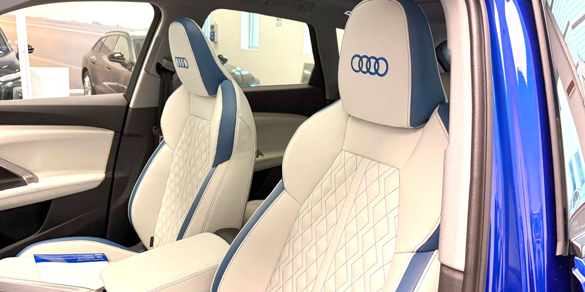 sedili anteriori auto bianchi con bordi e cuciture blu e logo Audi blu ricamato sul poggiatesta