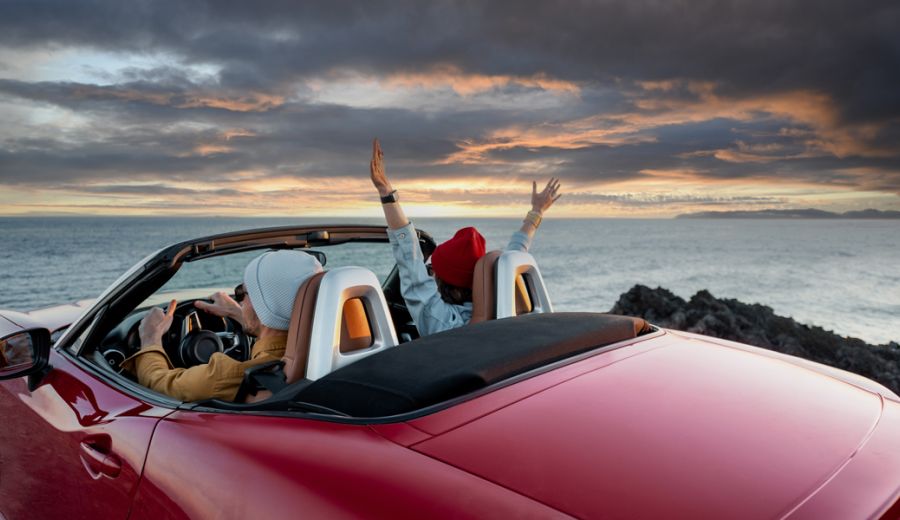 auto cabrio di fronte al mare con 2 persone all'interno