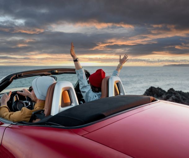 auto cabrio di fronte al mare con 2 persone all'interno