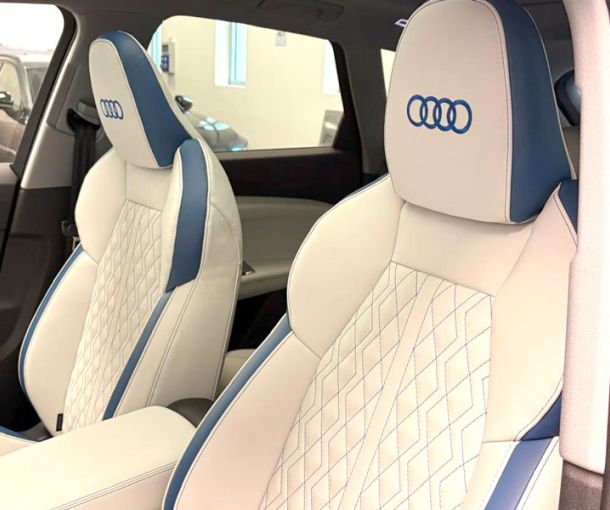 sedili anteriori auto bianchi con bordi e cuciture blu e logo Audi blu ricamato sul poggiatesta