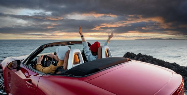 auto cabrio di fronte al mare con 2 persone all'interno